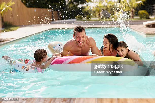 cheerful family having fun during summer day in the pool. - family swimming stock pictures, royalty-free photos & images