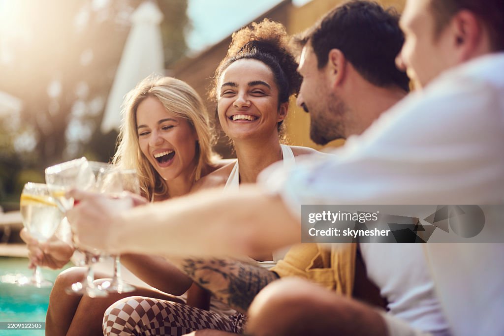 Junge fröhliche Freunde, die am Sommertag am Pool anstoßen.