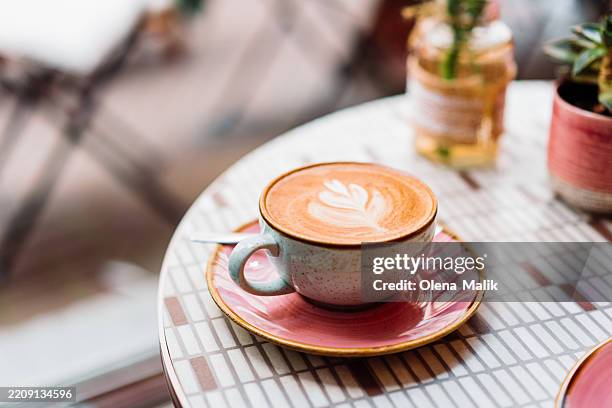 elegant latte art displayed on a vibrant ceramic cup with warm ambience - coffee bildbanksfoton och bilder