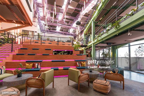 modern office interior with tiered stadium seating and industrial design elements - building atrium stock pictures, royalty-free photos & images
