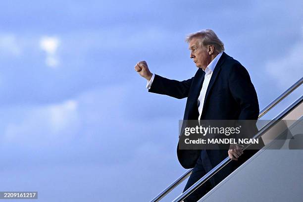 President Donald Trump raises a fist as he steps off Air Force One at Palm Beach International Airport in West Palm Beach, Florida, on April 11,...