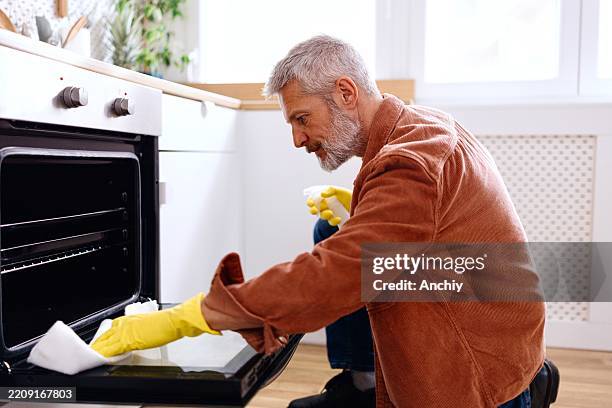 man cleaning a dirty oven in the kitchen - clean oven stock pictures, royalty-free photos & images