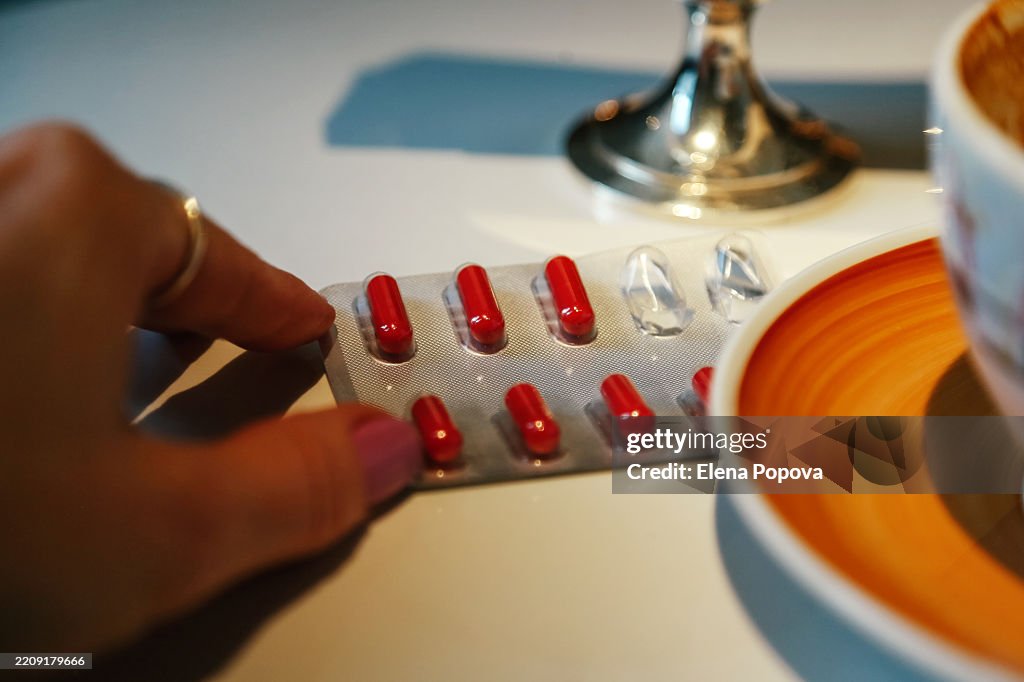 Medicine And Healthcare. Female's Hand Taking Blister Pack With Red Iron Capsules During Coffee Break