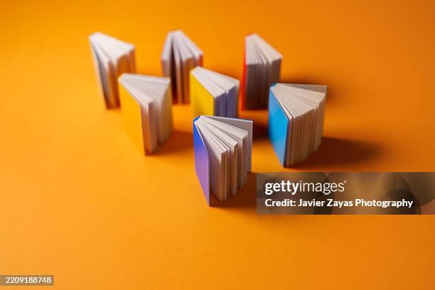 colorful books standing on orange background - biographie stock-fotos und bilder