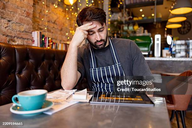 coffee shop owner looking worried while doing the accountancy - bankruptcy stock pictures, royalty-free photos & images