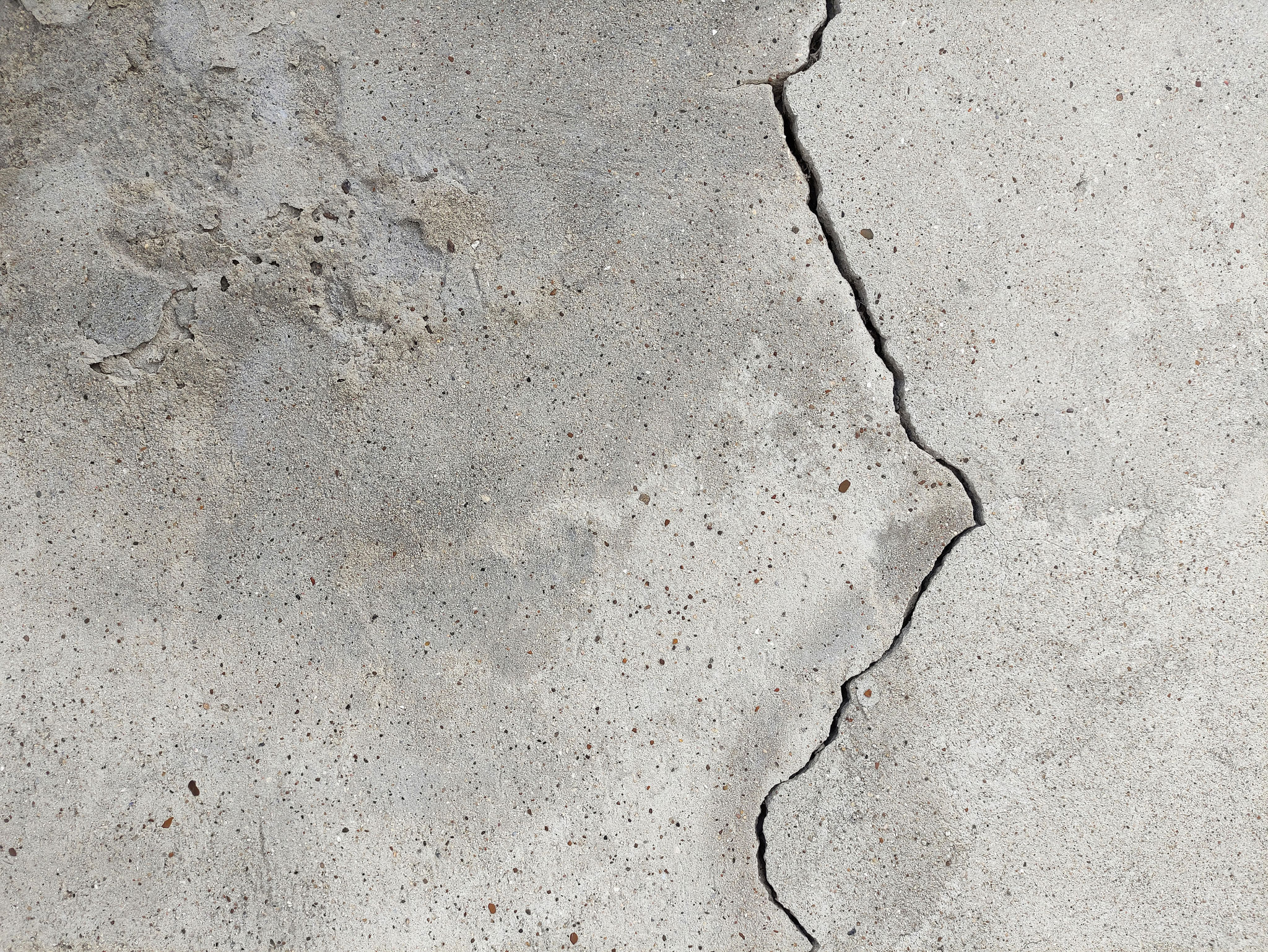 An old cracked, concrete wall with crumbling plaster from old age An old cracked, concrete wall with crumbling plaster from old age