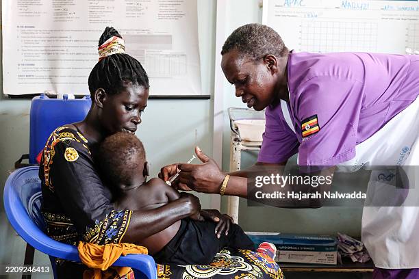 Hellen Akullo, Nurse Assistant administers the injection of the malaria vaccine to a baby at Apac General Hospital on April 8, 2025 in Apac District,...