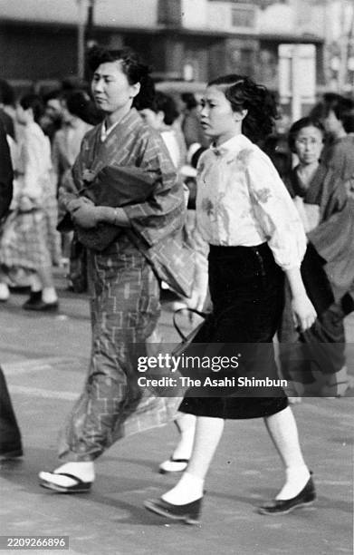 Women in kimono and a western style walk on the street circa 1930 in Japan.
