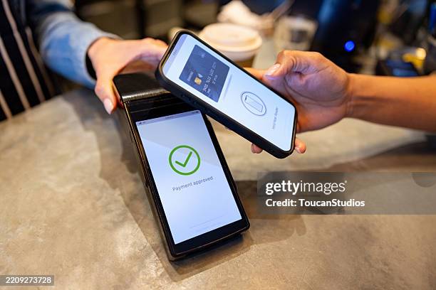 close-up em um cliente fazendo um pagamento móvel em um café - comunicação por campo de proximidade - fotografias e filmes do acervo