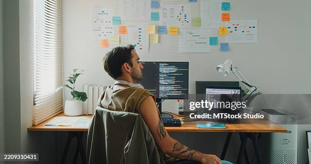 young gay computer programmer working on ai prompts and web page designs coding user experience on laptop in bedroom at home. software developer, artificial intelligence and programming. - java code stock pictures, royalty-free photos & images