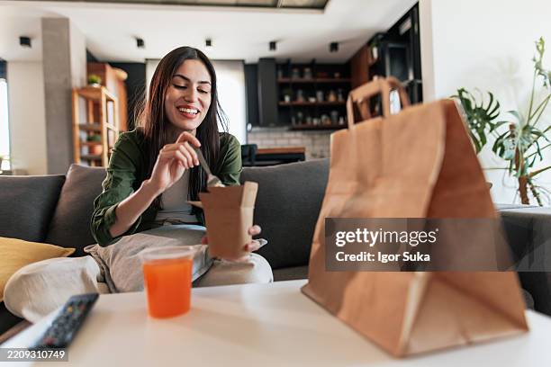 giovane donna che gode di cibo da asporto a casa - junk food foto e immagini stock