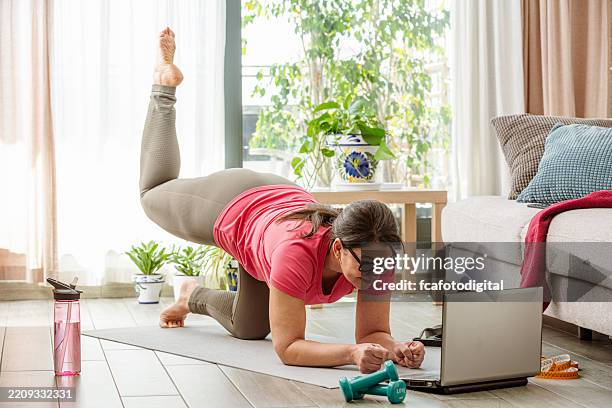 woman doing exercises while watching workout video. using laptop while doing plank position - bodyweight training stock pictures, royalty-free photos & images
