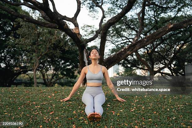 close-up shot of woman's bare feet lying on the grass, embracing the grounding and therapeutic benefits of nature - lichaamsbewustzijn stockfoto's en -beelden