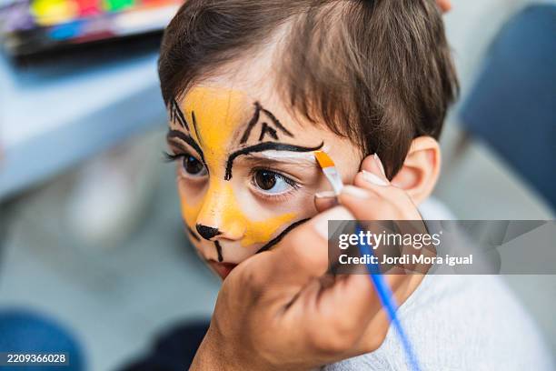 face painter applying lion makeup to child at local fair - face paint stock pictures, royalty-free photos & images