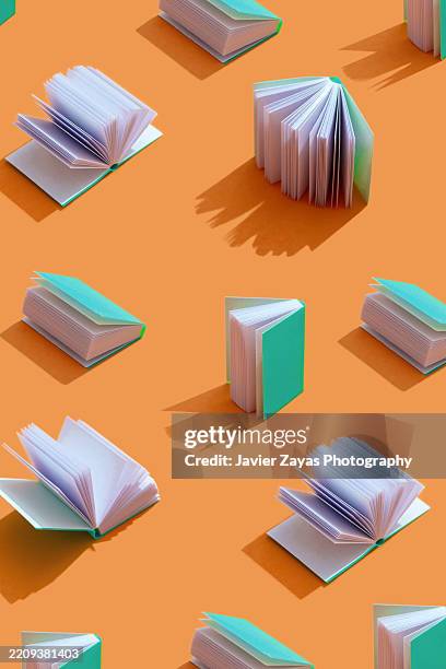 pattern of open and closed mini books casting a shadow on orange background - book publishing stock pictures, royalty-free photos & images