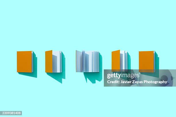 five orange books opening on a turquoise background, from closed to open - libro rilegato foto e immagini stock