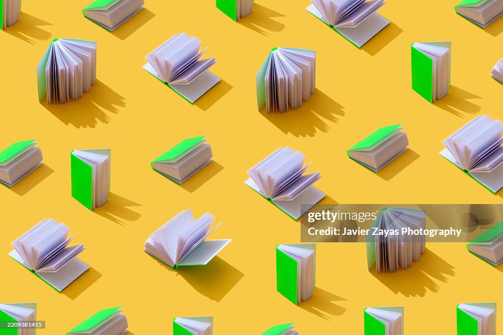 Pattern of miniature books with bright green covers on a yellow background