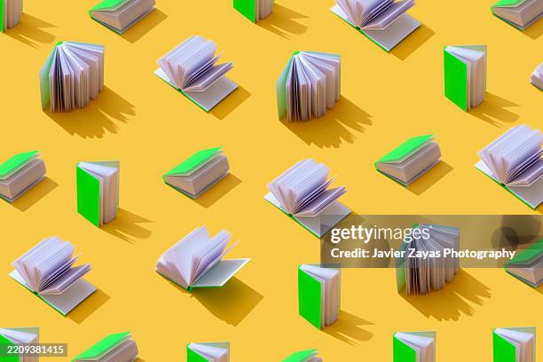 pattern of miniature books with bright green covers on a yellow background - libro rilegato foto e immagini stock