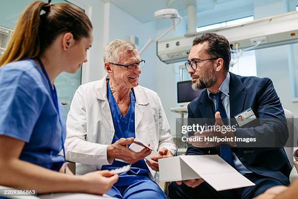 pharmaceutical sales respresentative showing doctors new medications. group presentation in hospital setting. - hospital director stock pictures, royalty-free photos & images