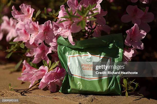 In this photo illustration, a Pimento Cheese sandwich is shown near azalea flowers during a practice round prior to the 2025 Masters Tournament at...