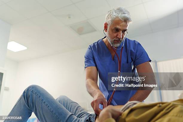doctor using stethoscope during abdominal examination on senior patient in emergency room. - appendix stock pictures, royalty-free photos & images