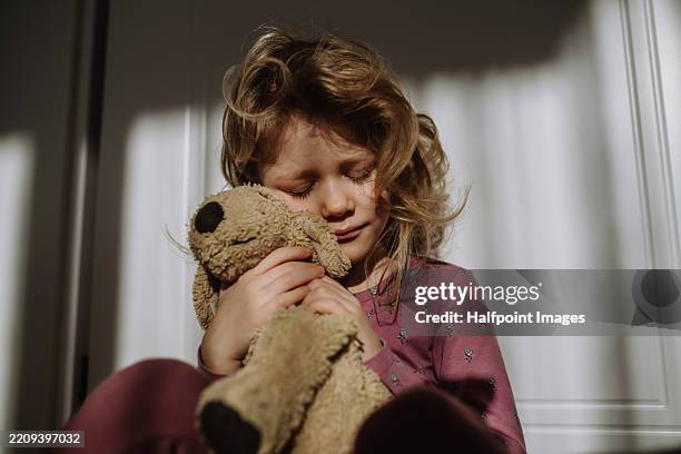 portrait of scared girl hugging her teddy bear plush toy. - stofftier stock-fotos und bilder