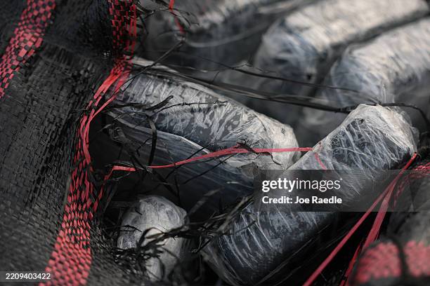 Bundles of drugs are seen as U.S. Coast Guard crew members offload cargo that was part of over $509 million in cocaine and marijuana seized during 13...