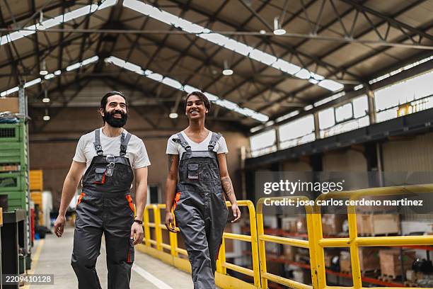 happy workers walking through warehouse while smiling at each other - manual worker stock pictures, royalty-free photos & images