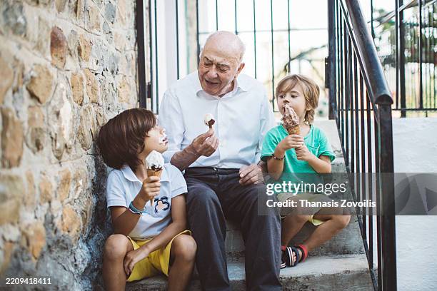 grandfather enjoying ice cream on a sunny day with his grandson outdoor - greek food stock pictures, royalty-free photos & images