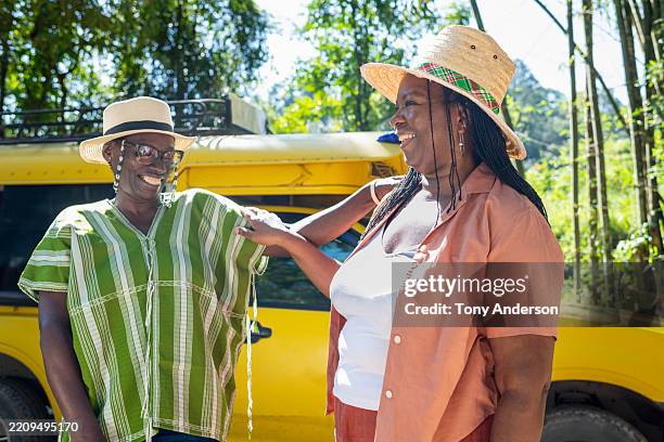 two senior women talking excitedly while arriving at outdoor travel destination - jamaicaanse etniciteit stockfoto's en -beelden