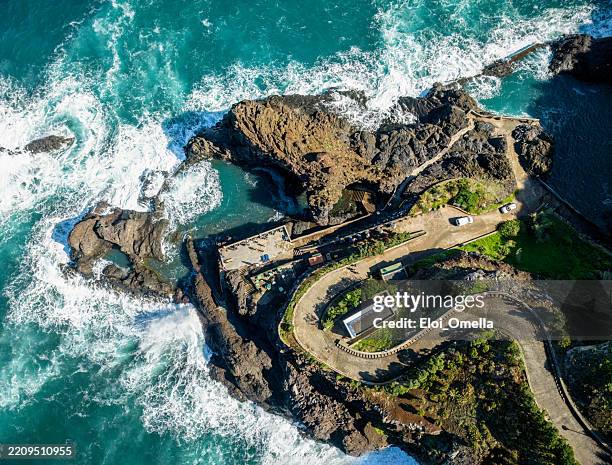 carretera serpenteante que desciende hacia las piscinas volcánicas naturales de porto monizseixal, madeira, portugal, con las olas del océano atlántico rompiendo contra la escarpada costa rocosa - vista marina fotografías e imágenes de stock