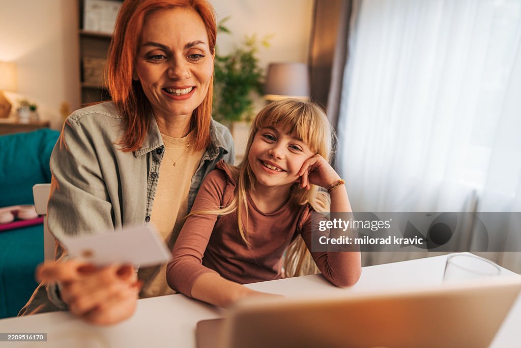 母と娘が自宅でクレジットカードを使ってオンラインショッピングをしている