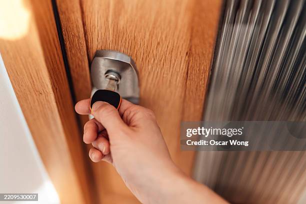 female hand locking the front door with key when leaving home - op slot doen stockfoto's en -beelden