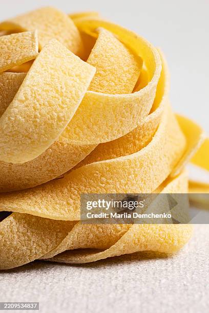 raw uncooked fettuccine pasta nest on gray background - stylisme culinaire photos et images de collection