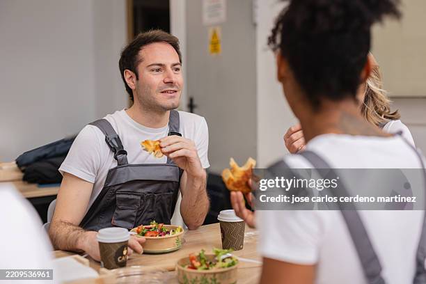 construction workers enjoying lunch break together - bib overalls stock pictures, royalty-free photos & images