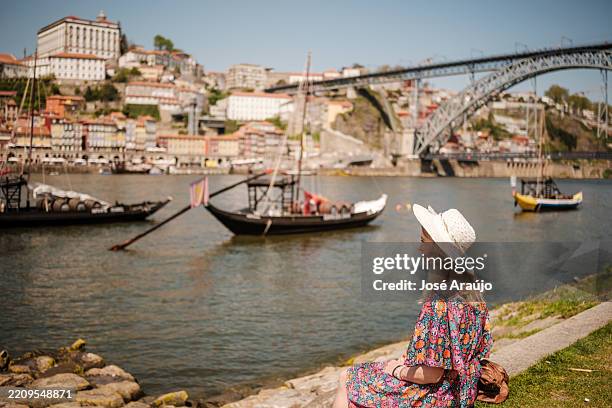 tourist enjoying douro river and dom luís i bridge in porto, portugal - porto stock pictures, royalty-free photos & images
