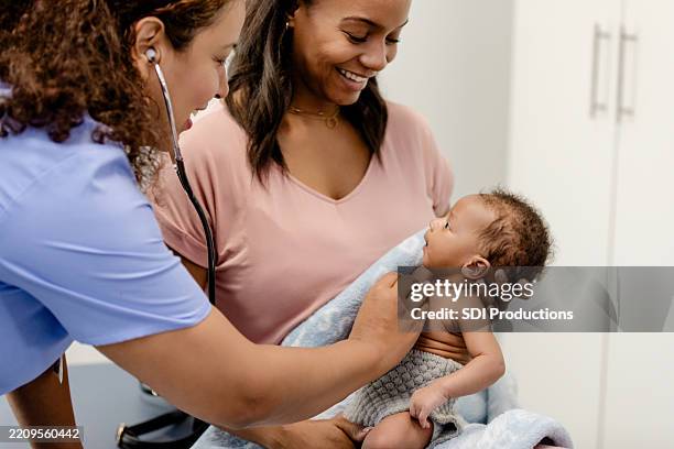 newborn baby checkup: doctor examining infant with mother - paediatrician stock pictures, royalty-free photos & images