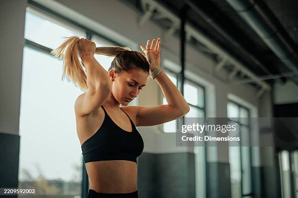 joven mujer atlética atando el cabello preparándose para entrenar en el gimnasio - cola de caballo cabello recogido fotografías e imágenes de stock