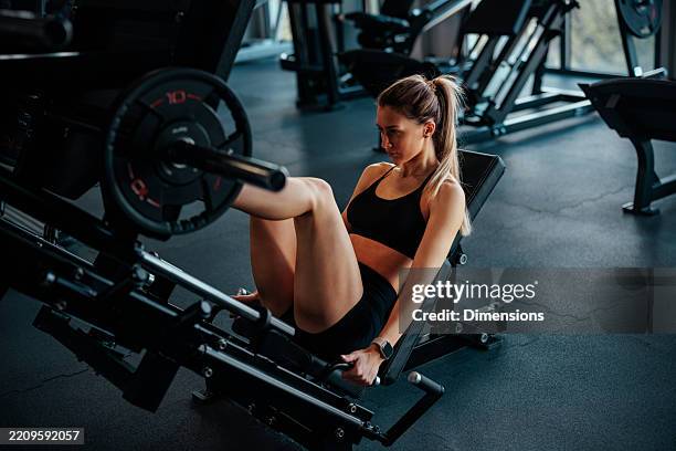 determined sportswoman doing leg press exercise at the gym - quadriceps muscle stock pictures, royalty-free photos & images