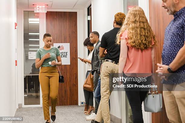 people waiting in line to vote at a polling place - plaatselijk overheidsgebouw stockfoto's en -beelden