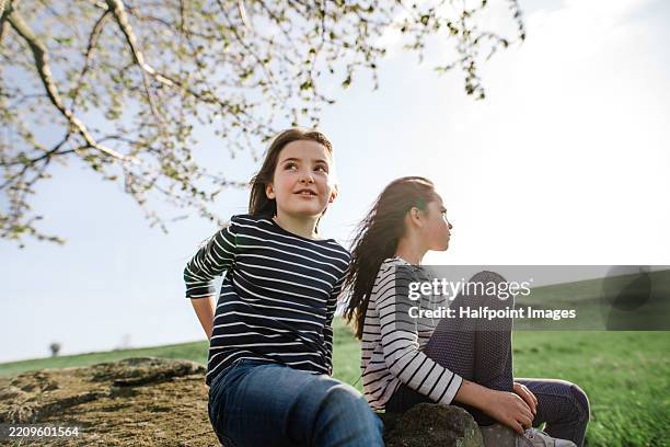 young female friends sitting in grass, enjoying spring weather. - freizeitaktivität im freien stock-fotos und bilder