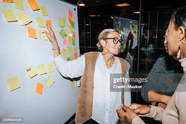 female professor explaining to students while standing near whiteboard in college - flash stock pictures, royalty-free photos & images