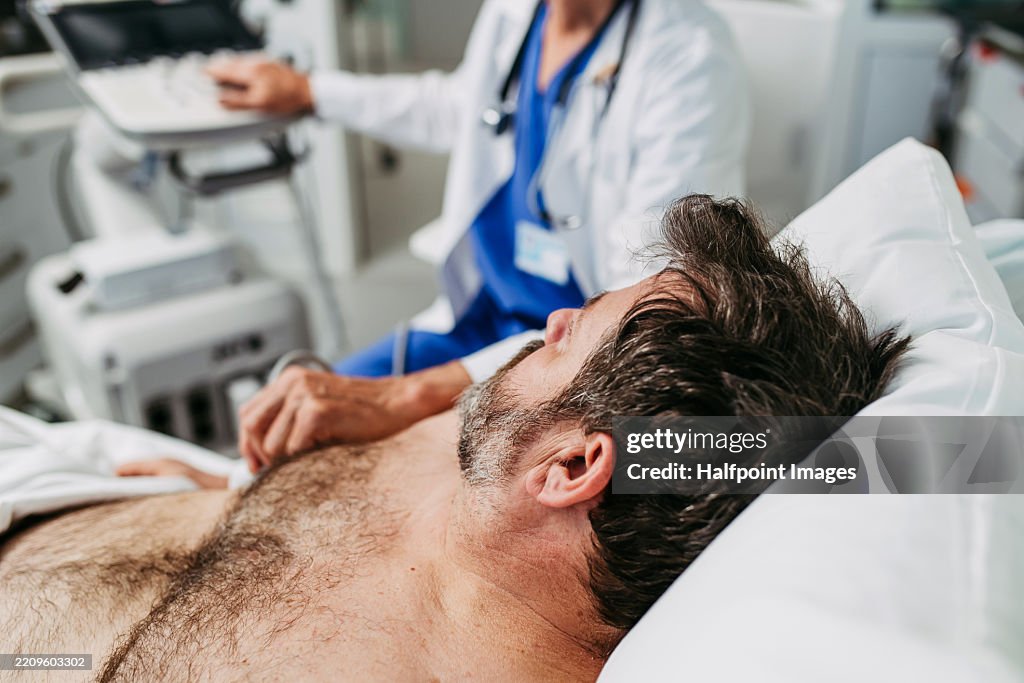 Close up of doctor performing an ultrasound on male patient's abdomen