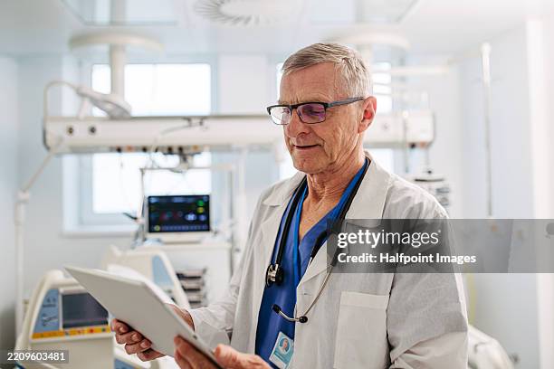 portrait of older doctor reading medical test results. - oncologist stock pictures, royalty-free photos & images