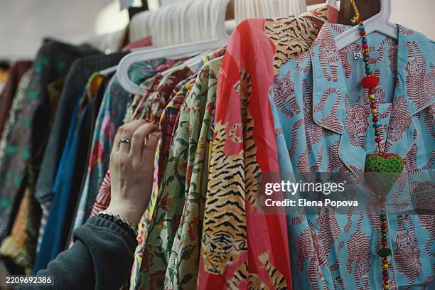 street flea market with fashionable colorful silk summer suits or pajamas on clothing racks, full frame, ambient light - pyjamas stock pictures, royalty-free photos & images