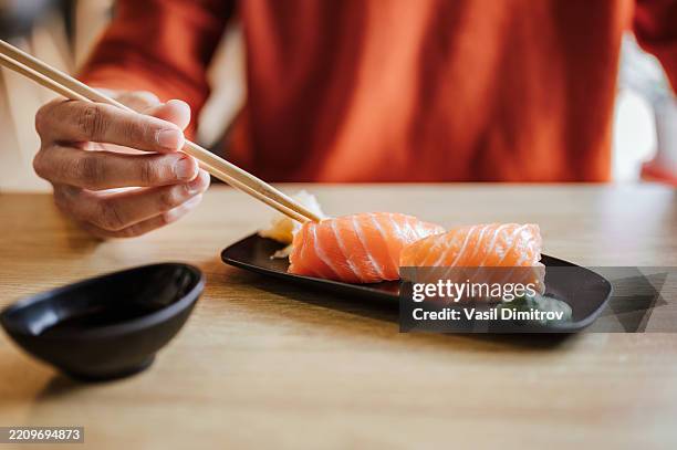unrecognizable man eating nigiri sushi with salmon. - sushi stock pictures, royalty-free photos & images