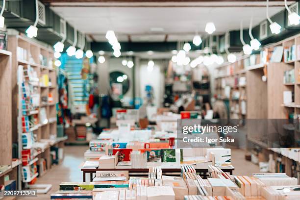 bookstore with many books lying on tables and shelves, creating a cozy atmosphere for reading and learning - bookstore stock pictures, royalty-free photos & images