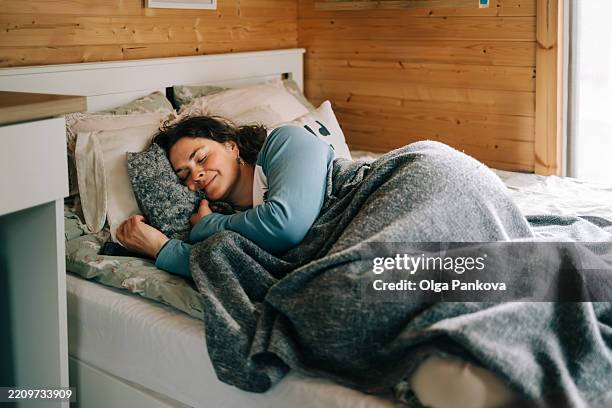 serene woman sleeping peacefully in cozy wooden cabin bedroom - hora de dormir fotografías e imágenes de stock