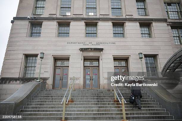 Person walks with an umbrella as rain falls on the U.S. Department of Agriculture building on April 11, 2025 in Washington, DC. President Donald...