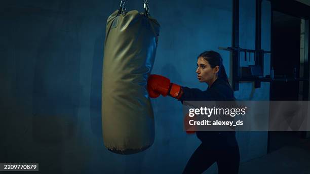 woman training with punching bag at home gym - boxing sport stock pictures, royalty-free photos & images